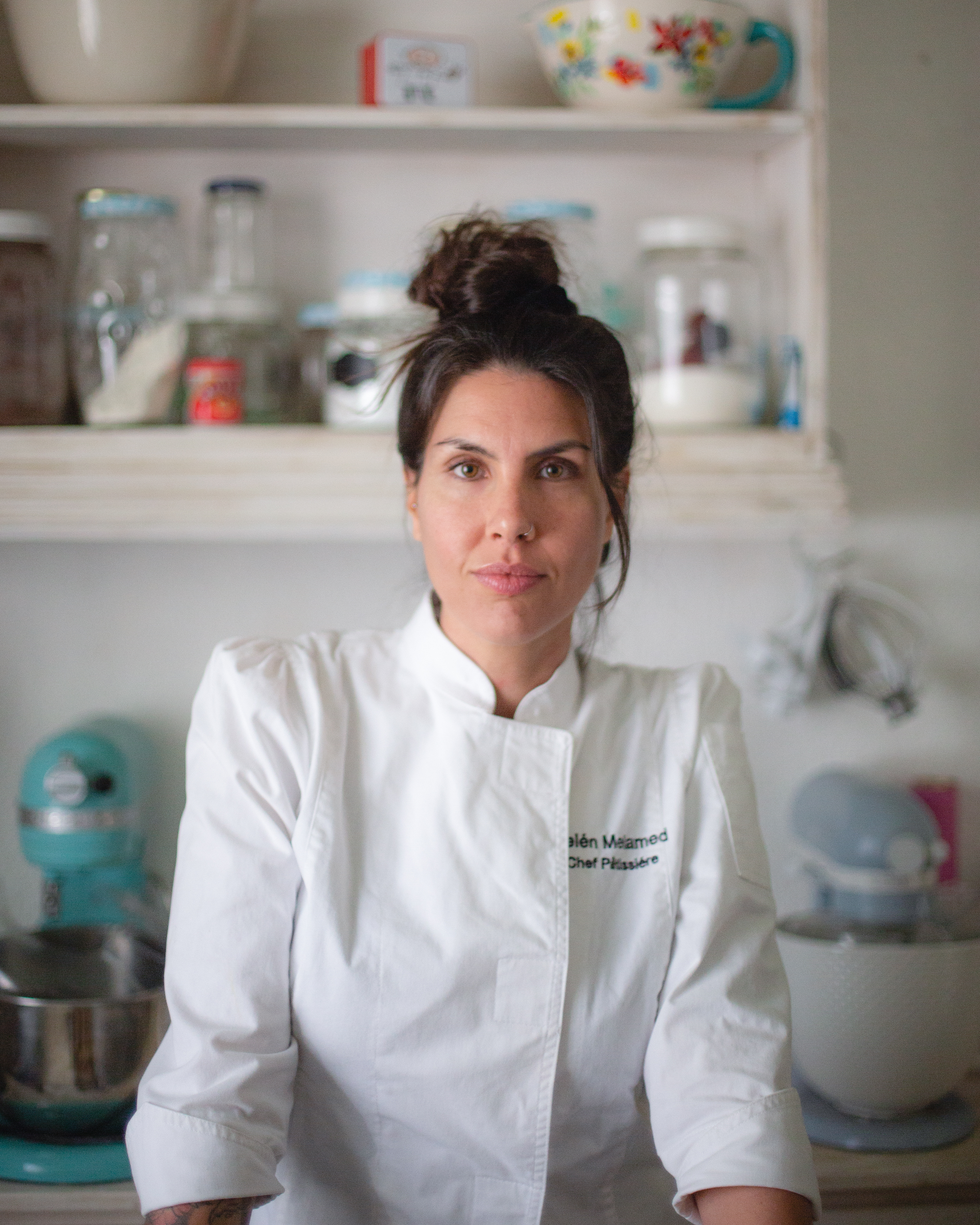 Belu Melamed, chef pastelera, con chaqueta blanca mirando a cámara